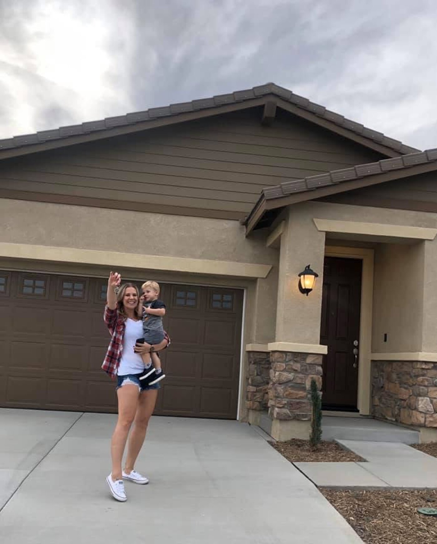 A happy homeowner holding her keys and her son in front of their new Menifee home