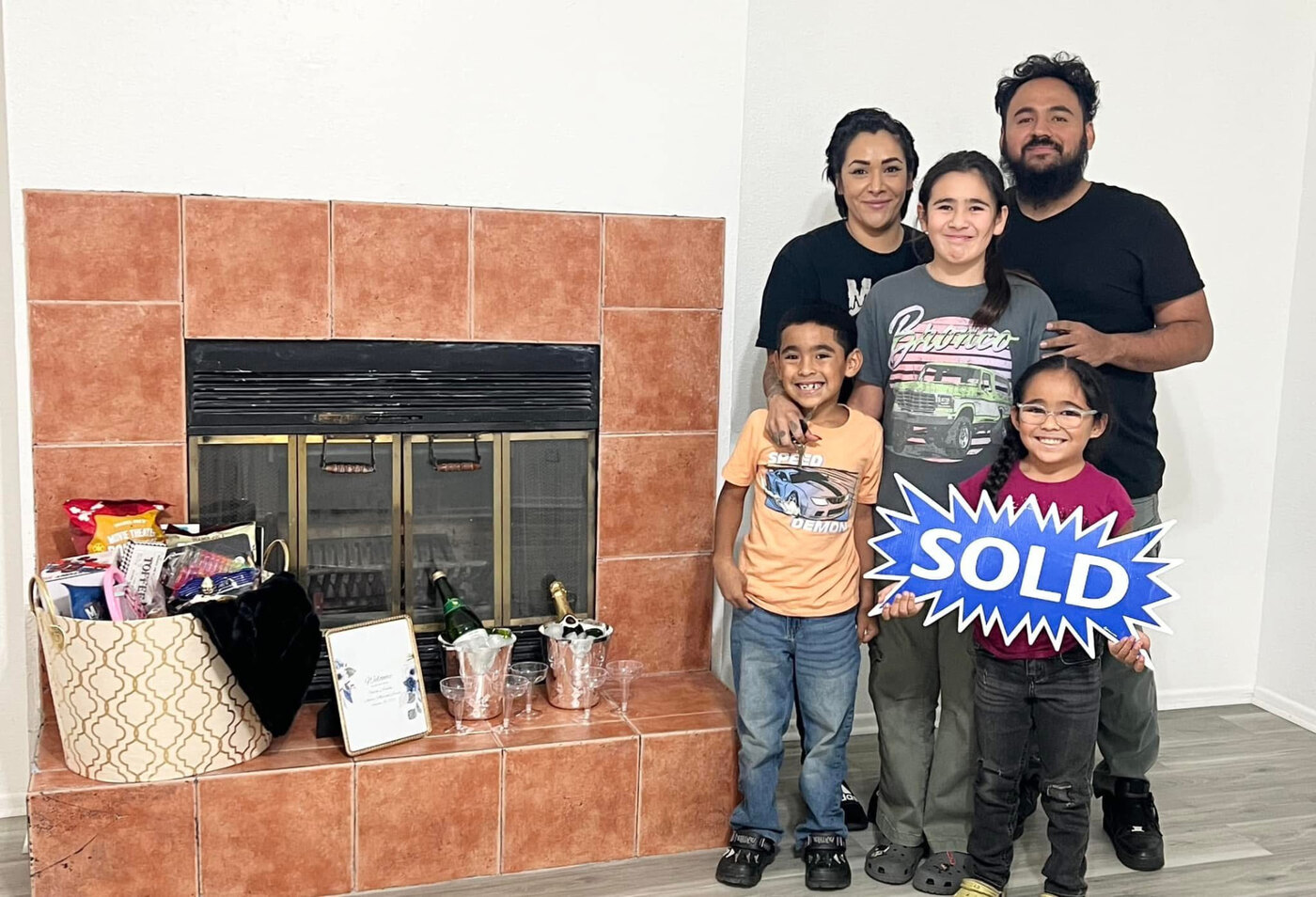 The Aguilar family holding a Sold sign inside their new Twentynine Palms home