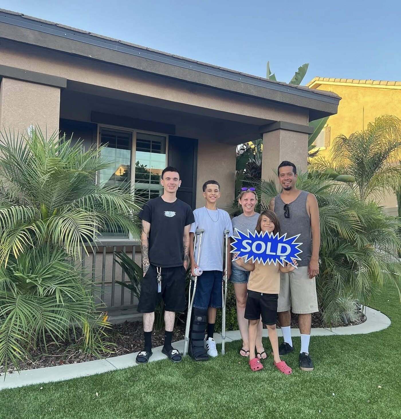 The Ornelas family holding a Sold sign in front of their new Perris home